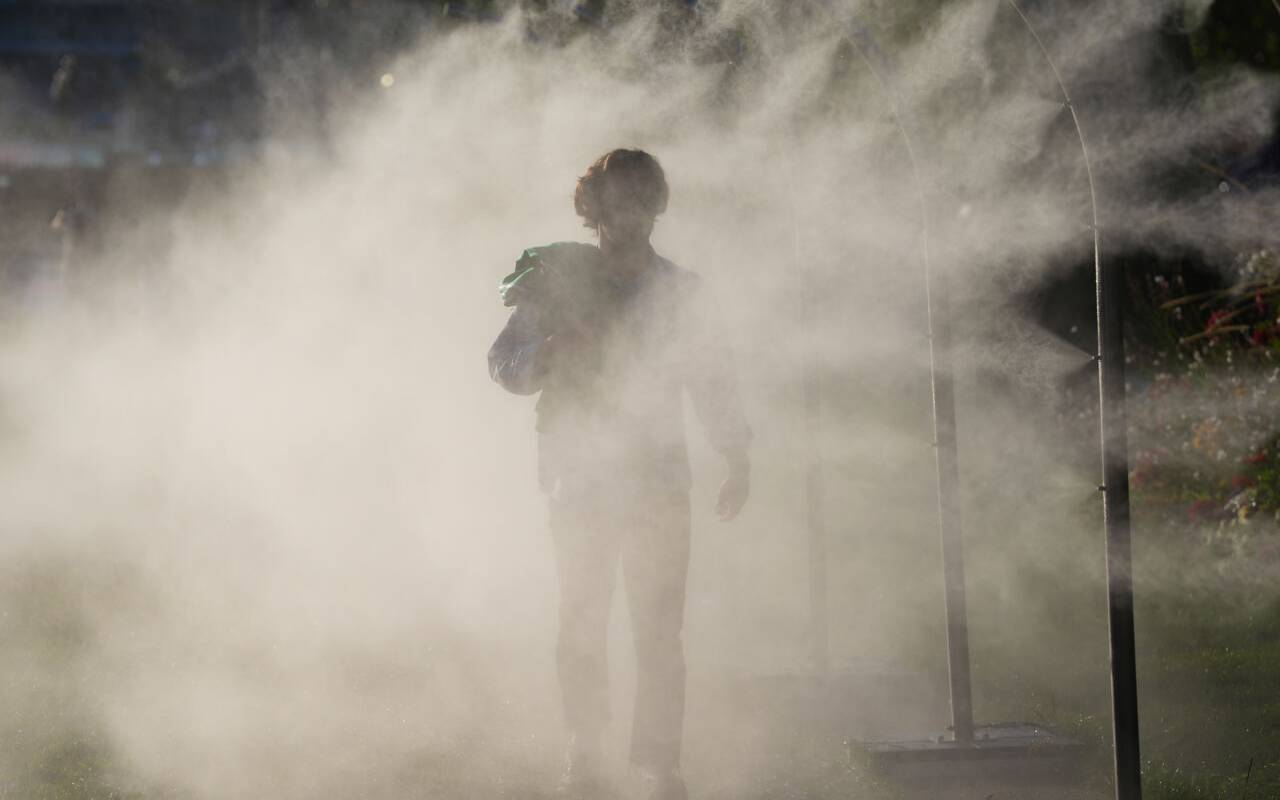 Olympia, Paris 2024, eine Person geht durch einen Sprühnebel-Zerstäuber und kühlt sich ab.