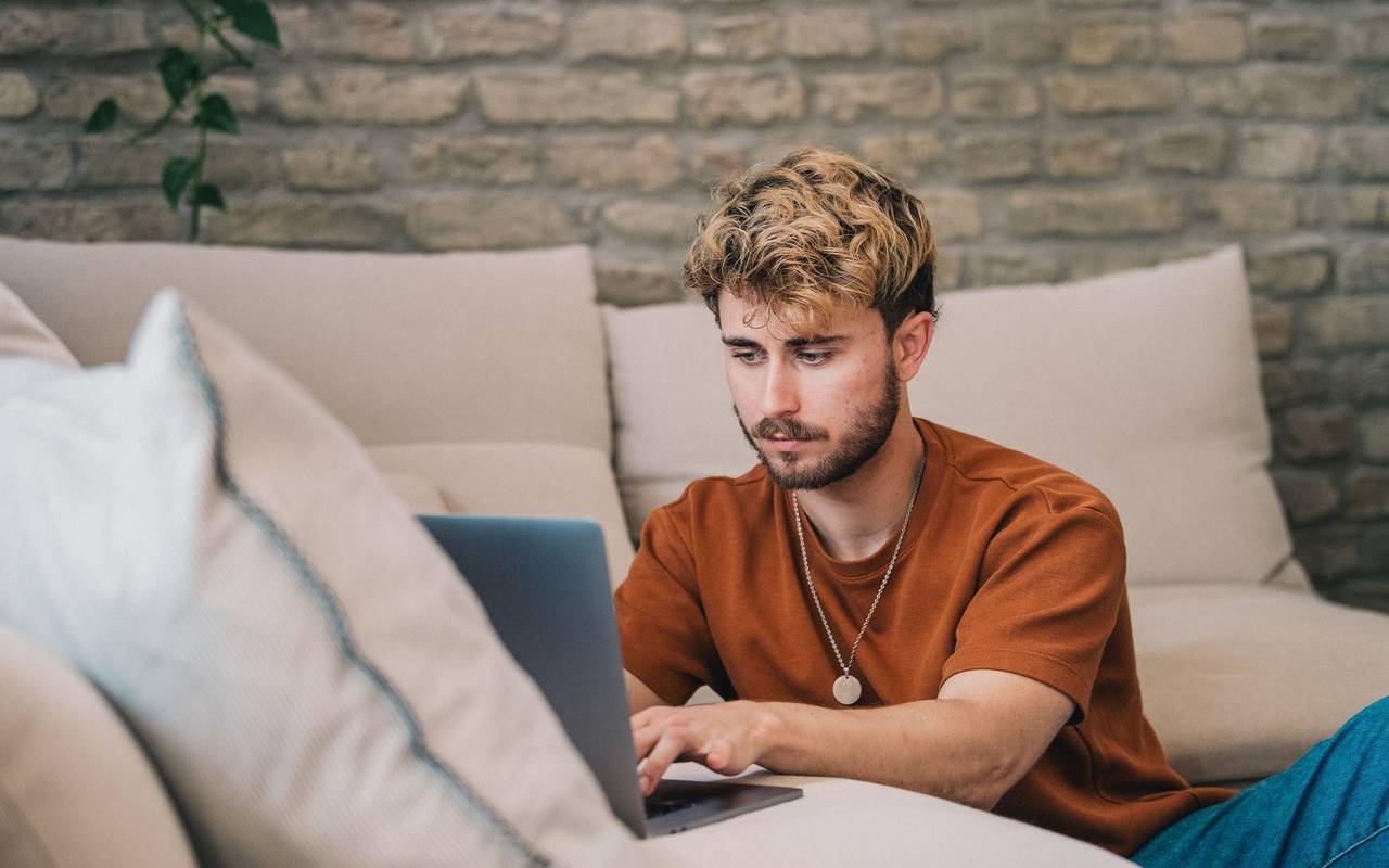 Ein Mann am Laptop auf einer Couch