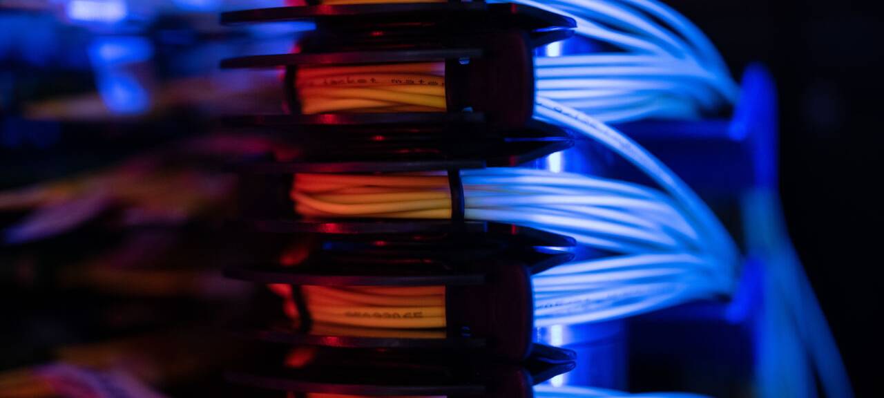 Glasfaserbündel liegen in einem Serverschrank.