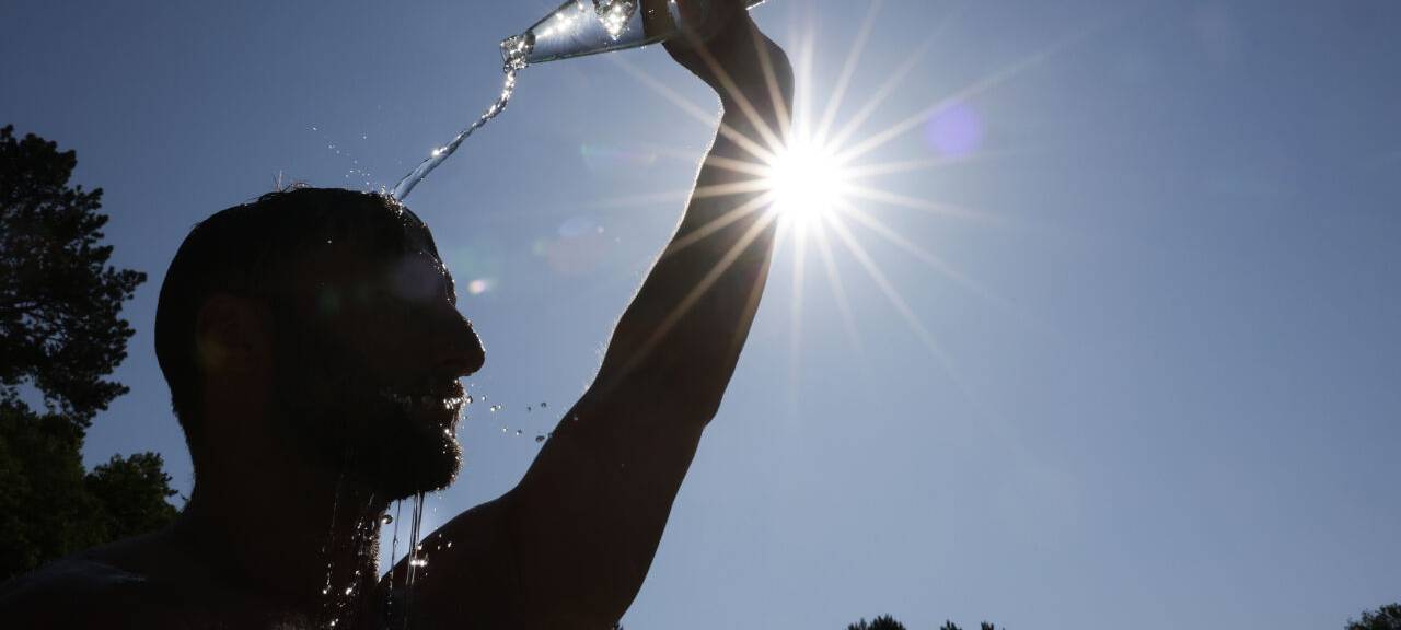 Ein Mann erholt sich von der Hitze, in dem er sich Wasser ins Gesicht spült.