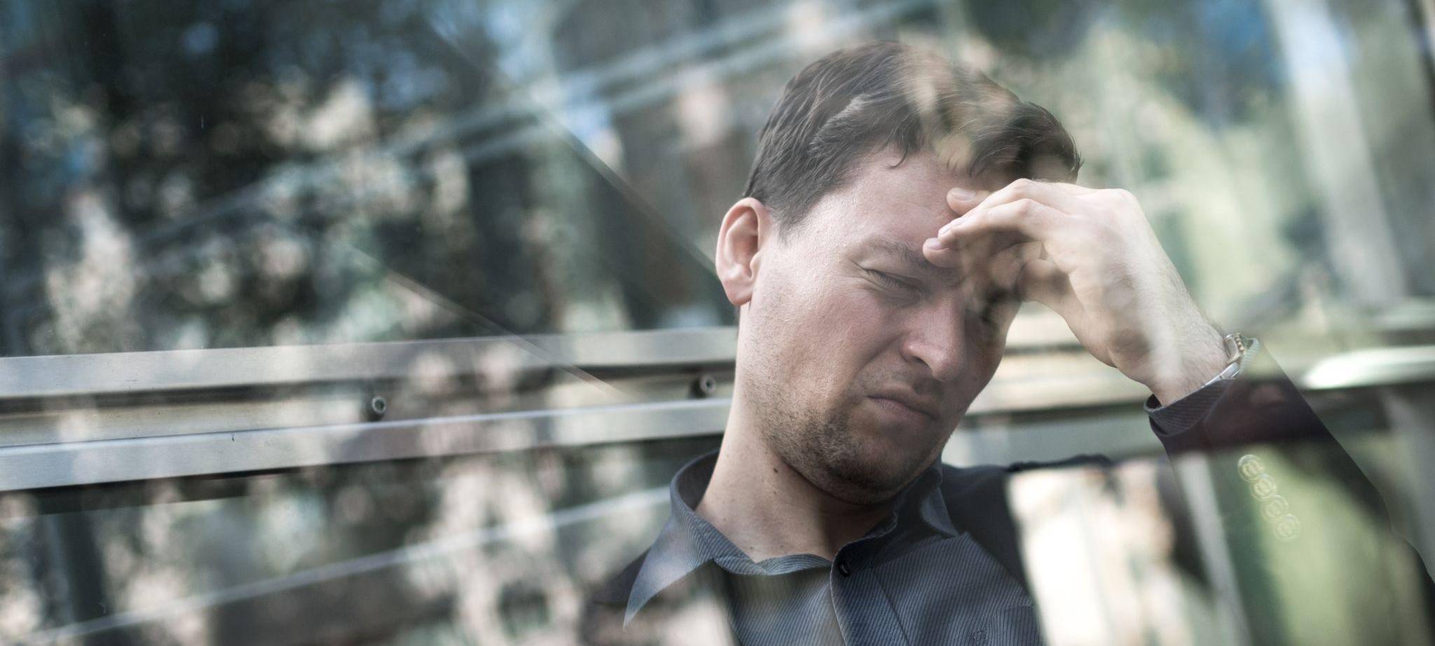 Mann hält sich mit der Hand seinen schmerzenden Kopf