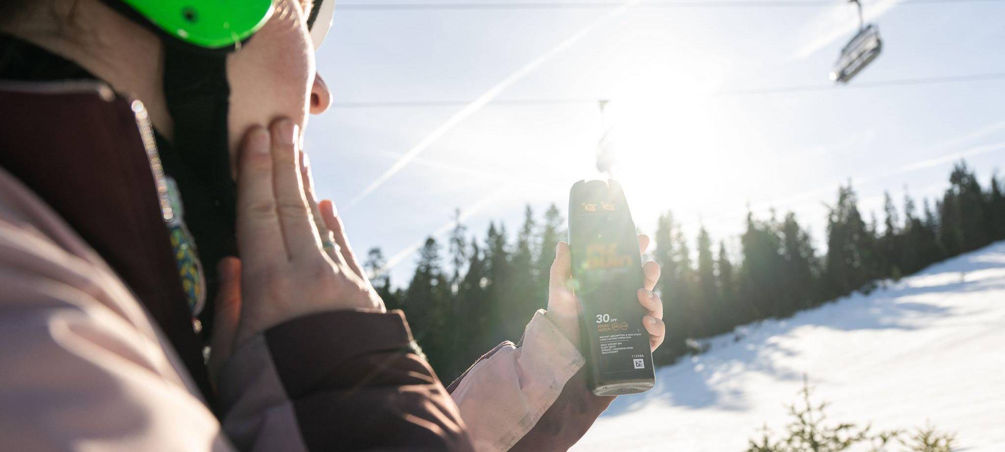Eine Skifahrerin trägt Sonnencreme auf