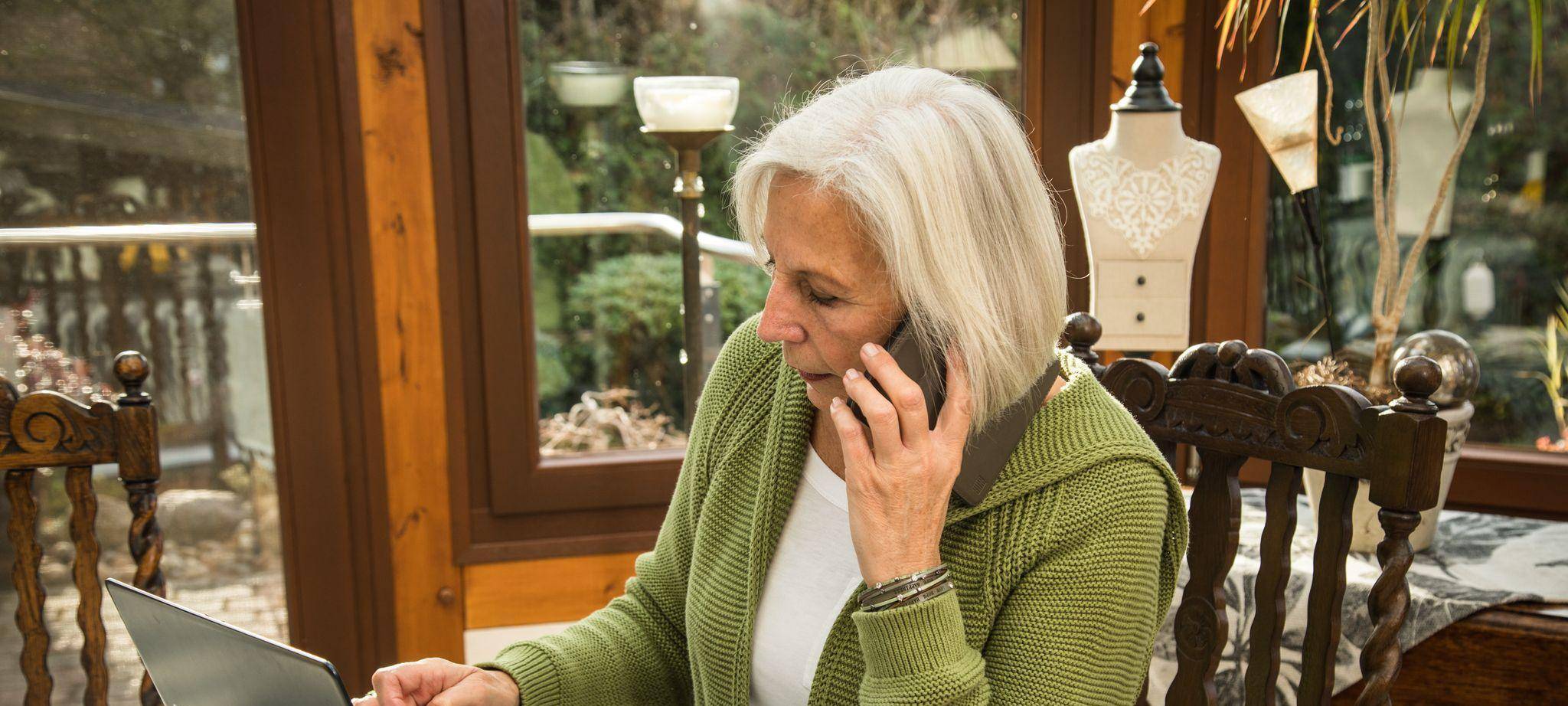 Seniorin mit Smartphone und Laptop