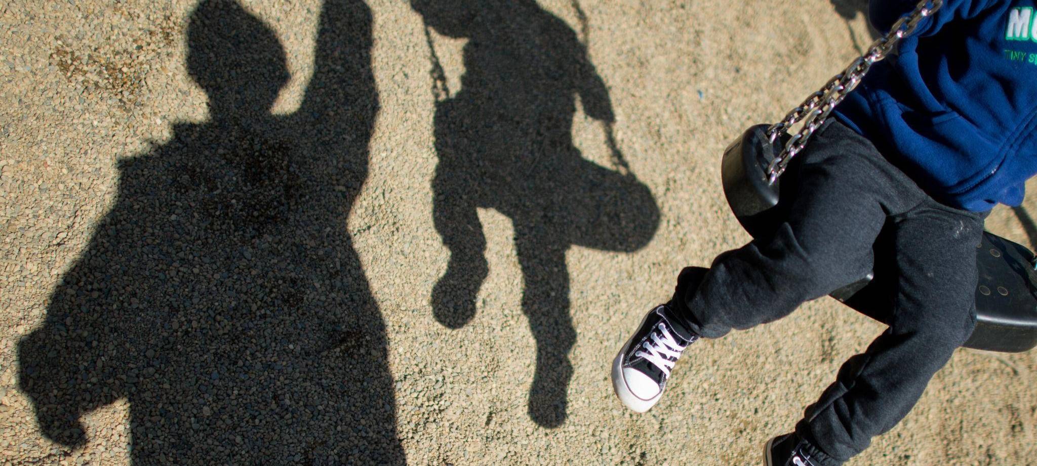 Ein Erwachsener schubst die Schaukel eines Kindes an
