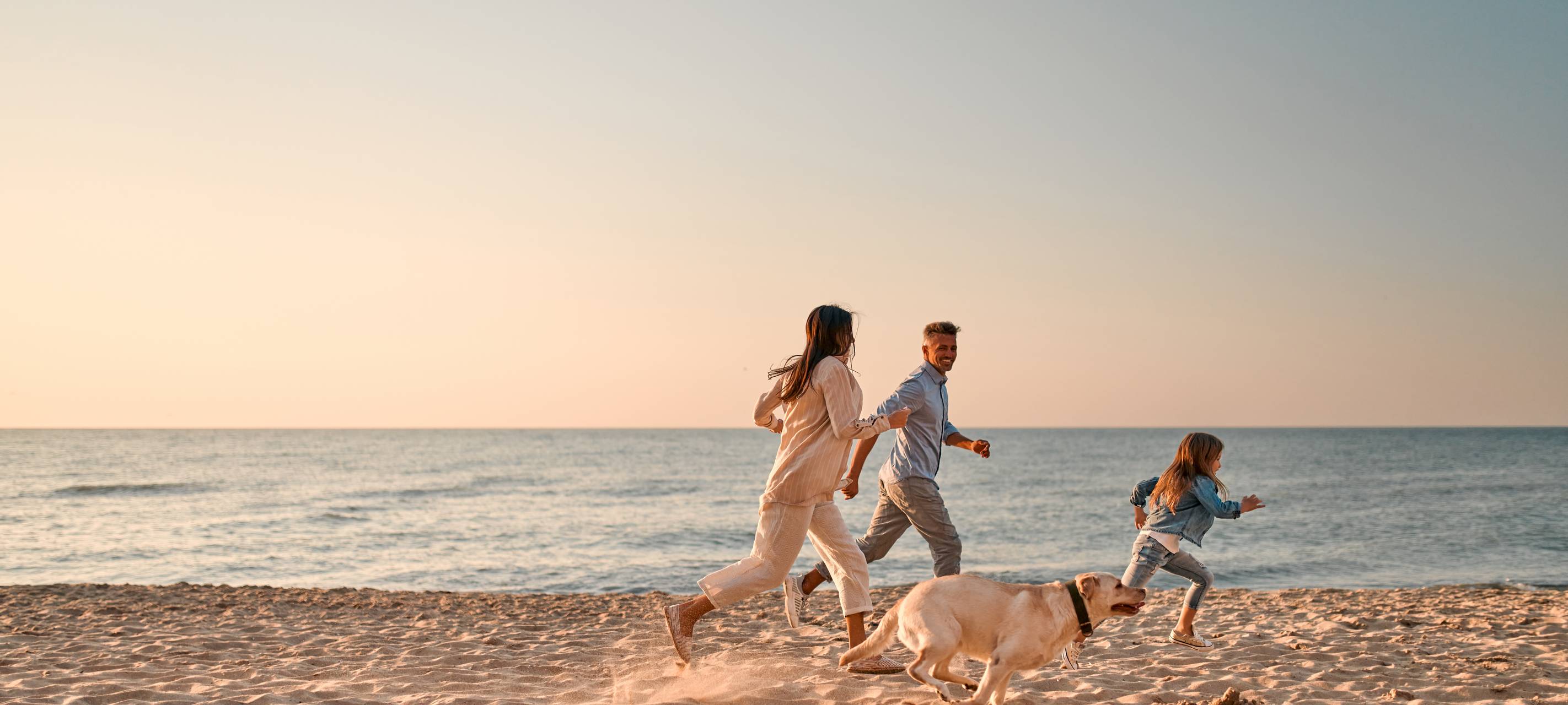 Glückliche Familie mit Hund am Strand