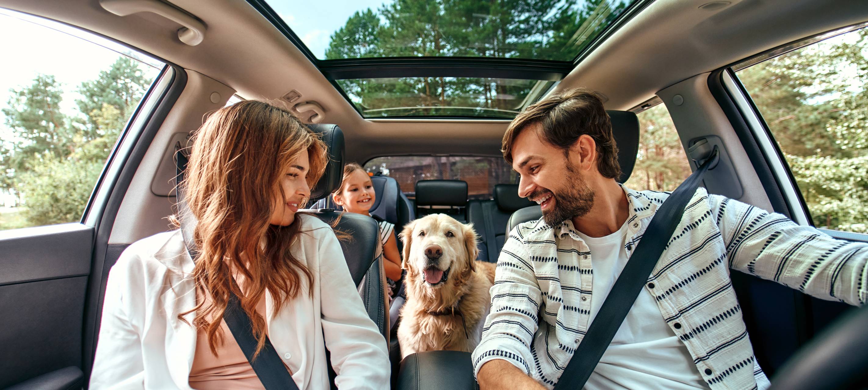 Glückliche Familie mit Hund im Auto