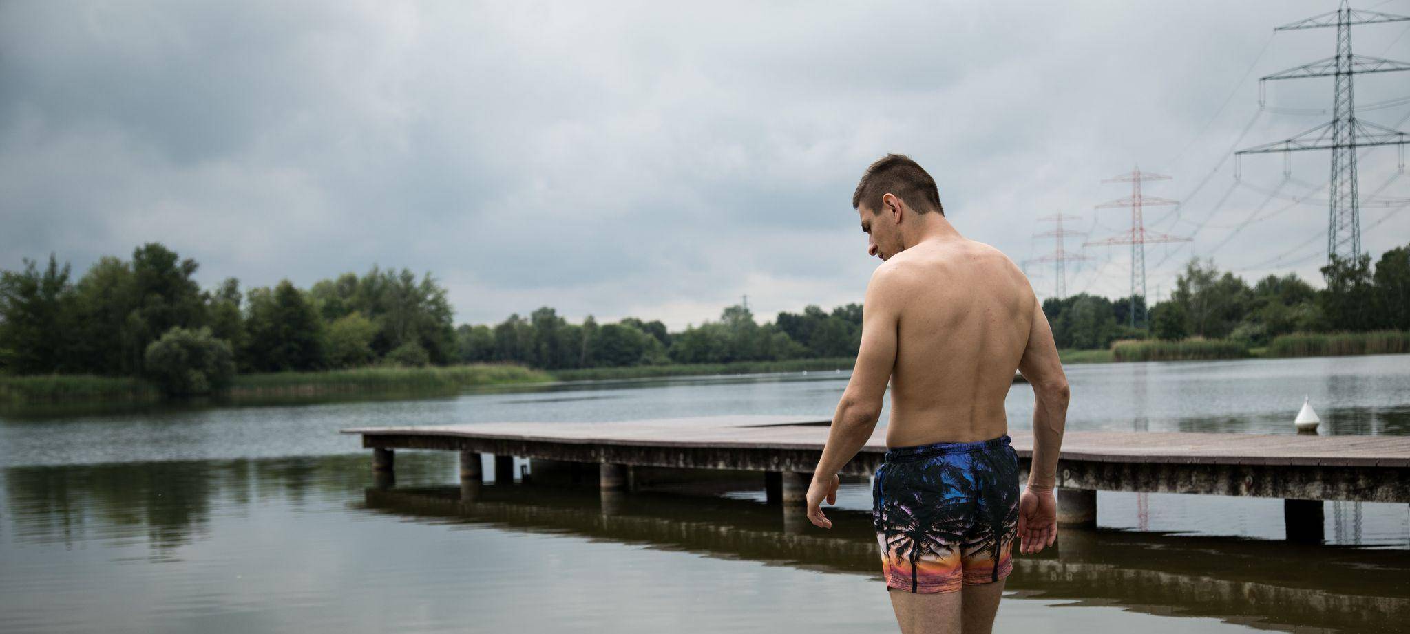 Ein Mann geht am an einem See baden