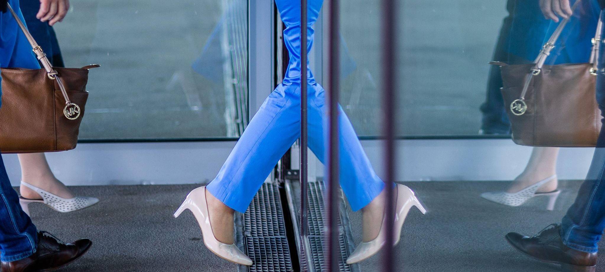 Eine geht Frau durch eine Tür und spiegelt sich in der Glasfront